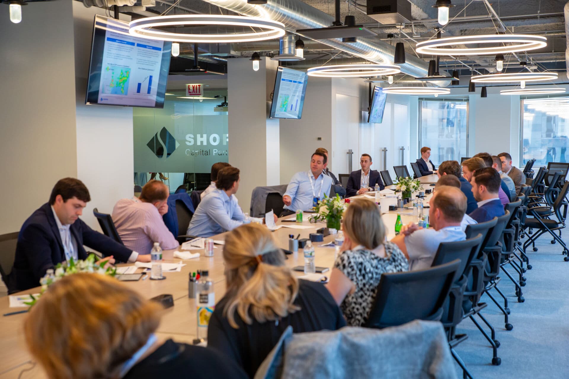 Long table of executives attend a meeting at Shore Capital Partners Office