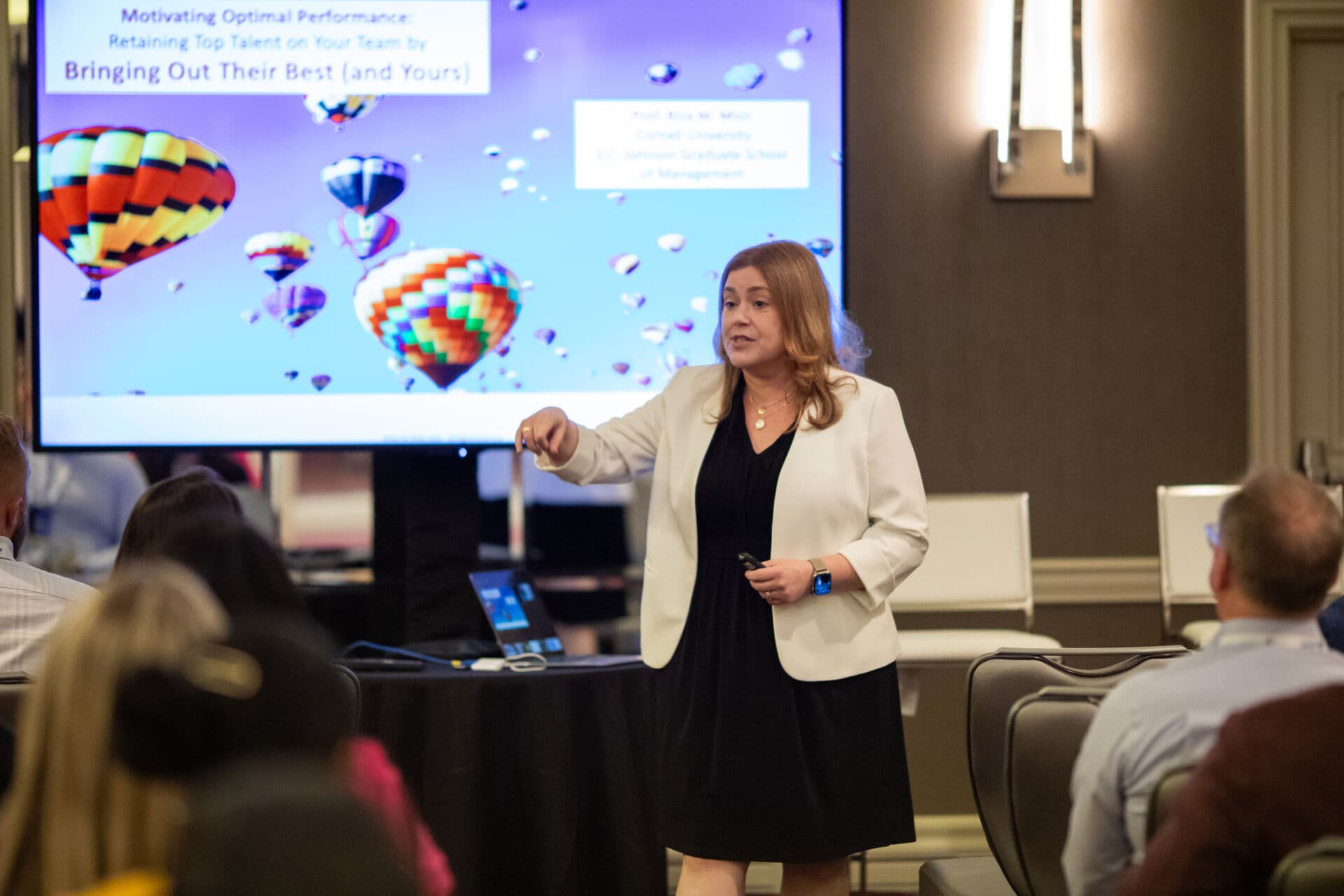 Female Presenter at Shore Capital Partners Executive Leadership Academy Breakout Session in front of display board
